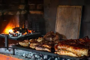 Different cuts of meat cooking on an open grill